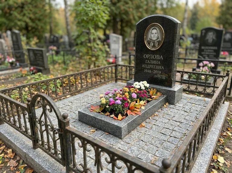 Благоустроенное захоронение с гранитной плиткой, оградой и цветником в Томске