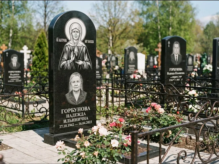 Памятник с гравировкой иконы: стела с арочным верхом и киотом под образ — гравировка образа Матроны Московской, гранитный цоколь с тёмной плиткой, работа «Ковалёв» в Томске