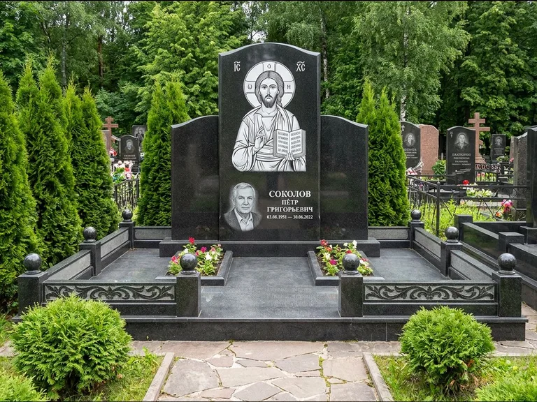 Памятник с гравировкой иконы: широкая горизонтальная лежачая плита-стела — икона в резной рамке-киоте, серая гравийная отсыпка с бордюром, работа «Богданова» в Томске