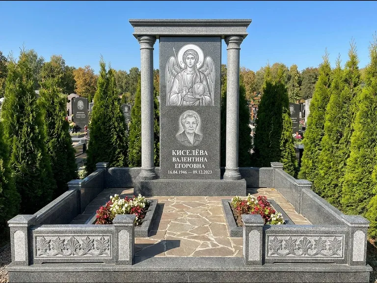 Памятник с гравировкой иконы: массивная стела с двускатным навершием-домиком — гравировка Николая Чудотворца, живая изгородь из туи, работа «Журавлёв» в Томске
