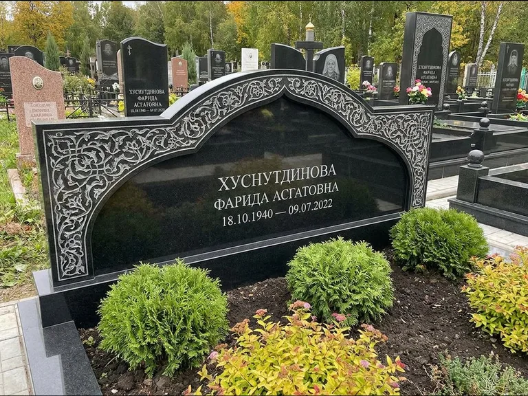 Мусульманский памятник: вытянутая горизонтальная семейная стела с аркой — белая гравировка силуэта мечети с минаретами, участок с декоративными кустами, работа «Зарипова» в Томске