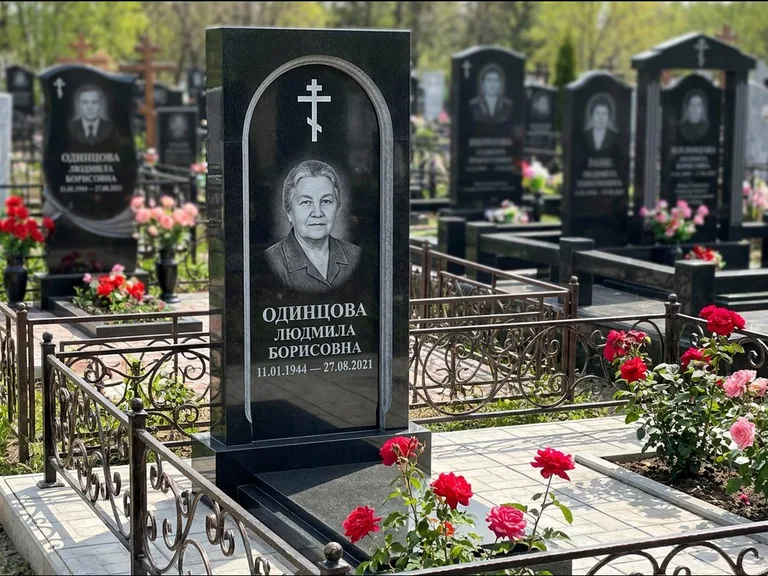 Памятник из чёрного гранита — скромная невысокая стела с крестом с терновым венцом, работа «Лаврентьева» в Томске