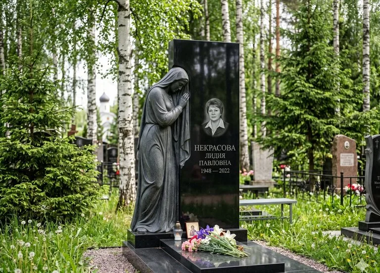 Гранитная фигура скорбящего мужчины у чёрной стелы в Томске