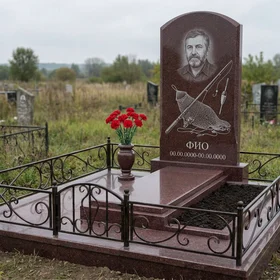 Гранитный памятник рыбаку в форме арки с рыбацкой лодкой